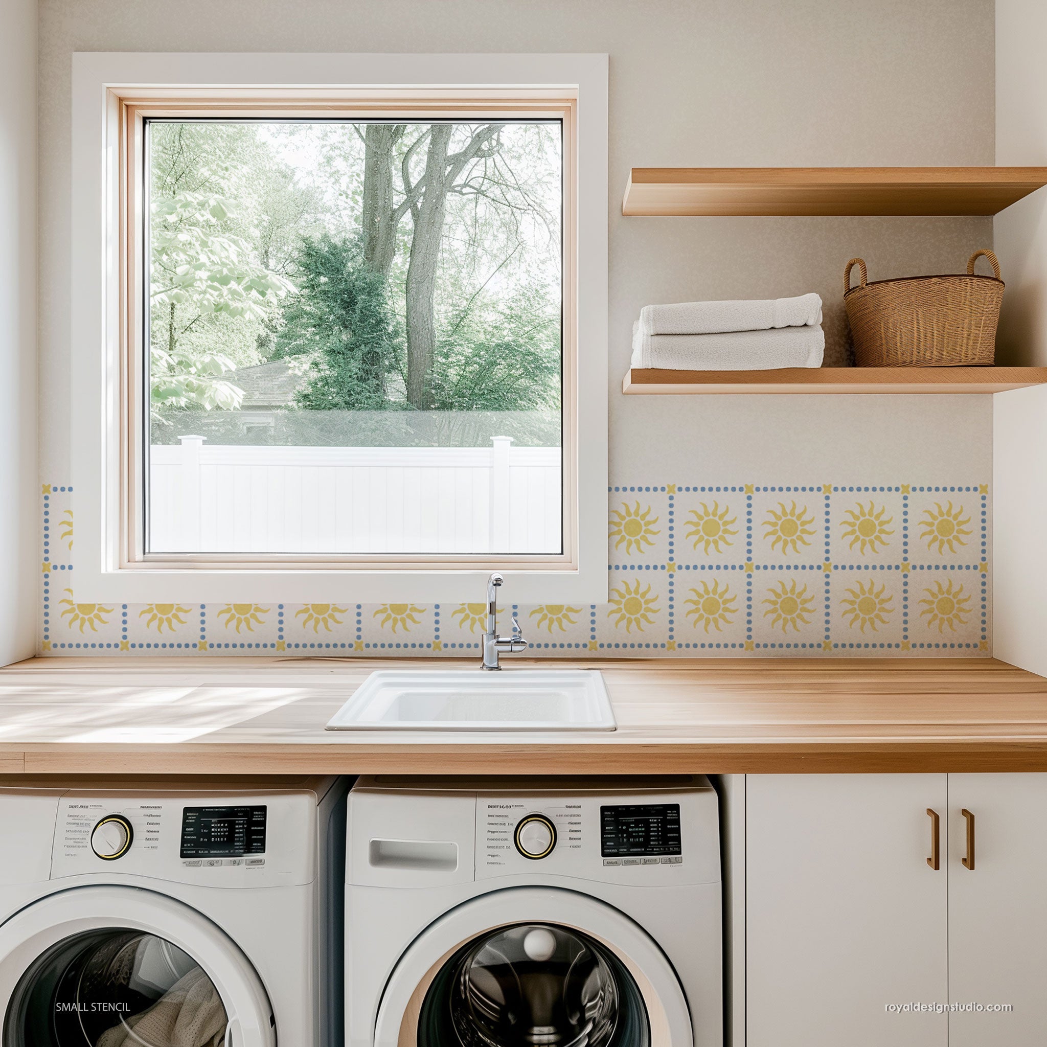 Laundry room wall stencikl with washing machines, wooden counter, and window