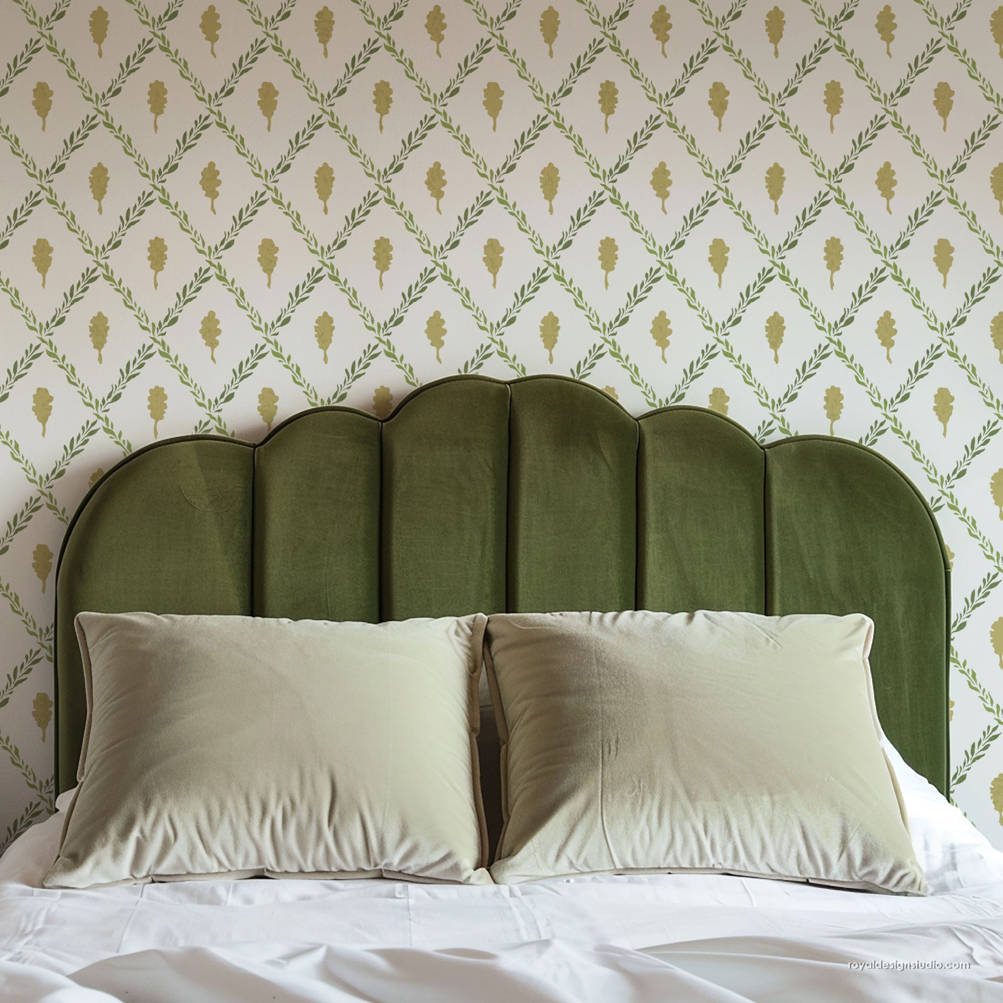 Green upholstered headboard with white pillows against a large trellis wall stencil background