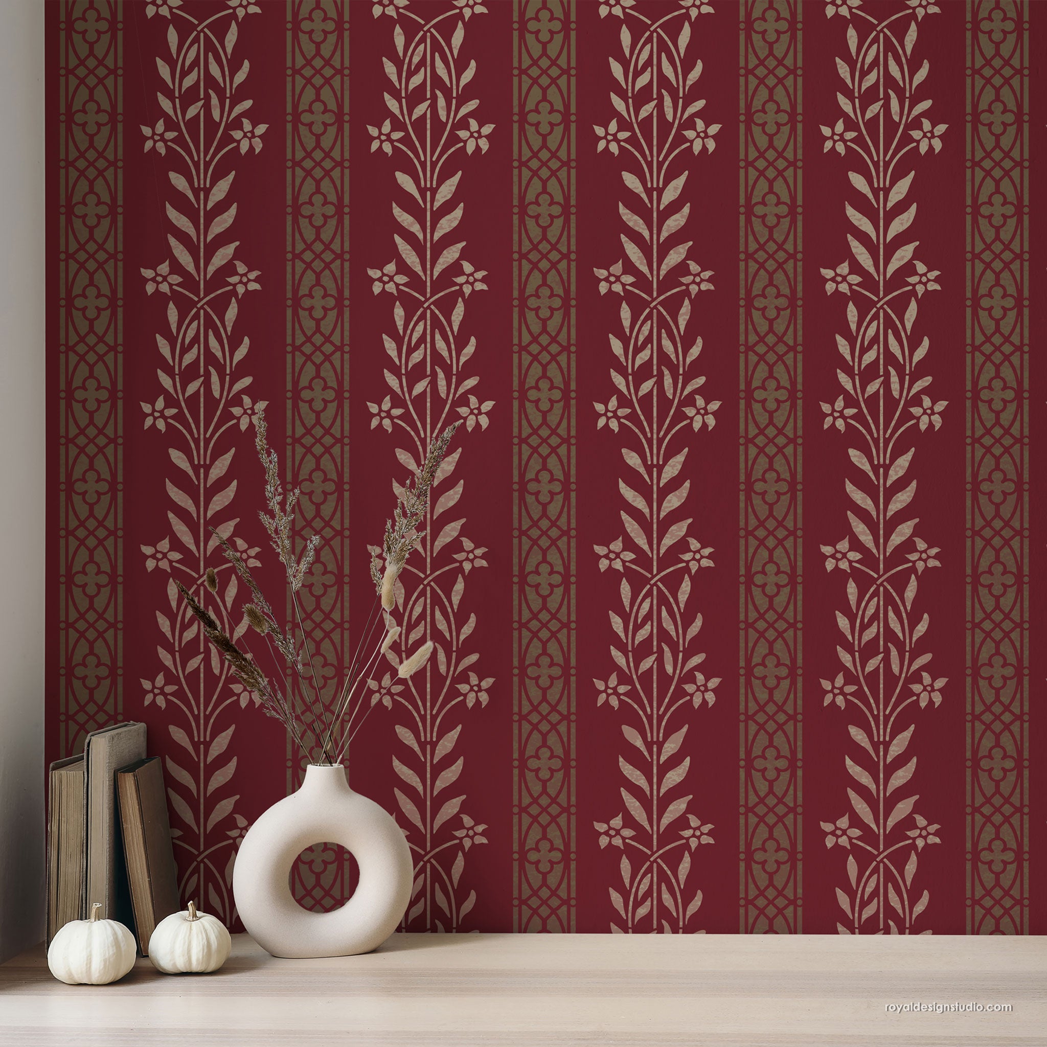 Decorative floral stenciled wallpaper with floral patterns on a red background, featuring a vase and books on a shelf.