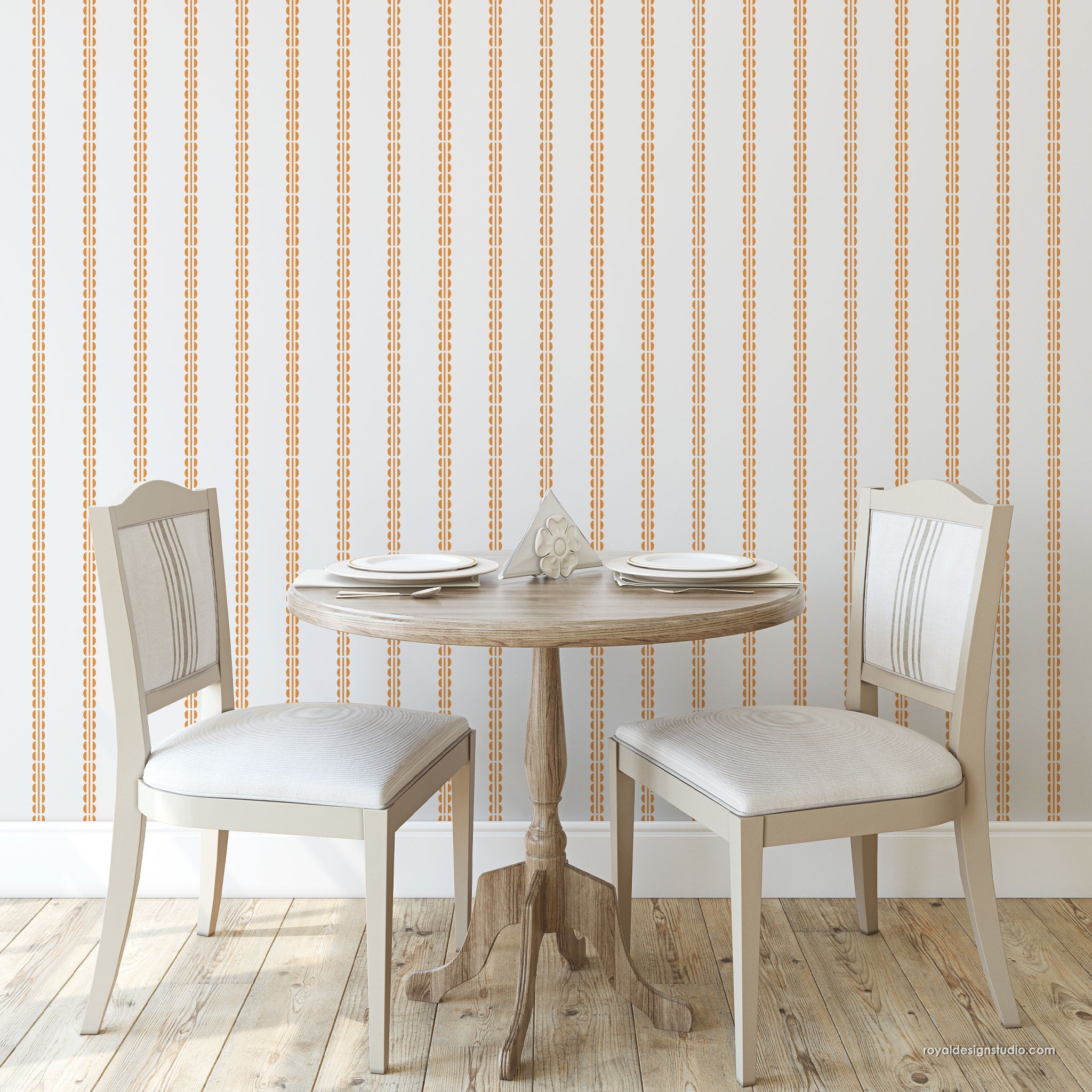 A styled dining room scene featuring a round wooden table set with two matching upholstered chairs, set against a wall with vertical dotted stripes in warm beige and white.