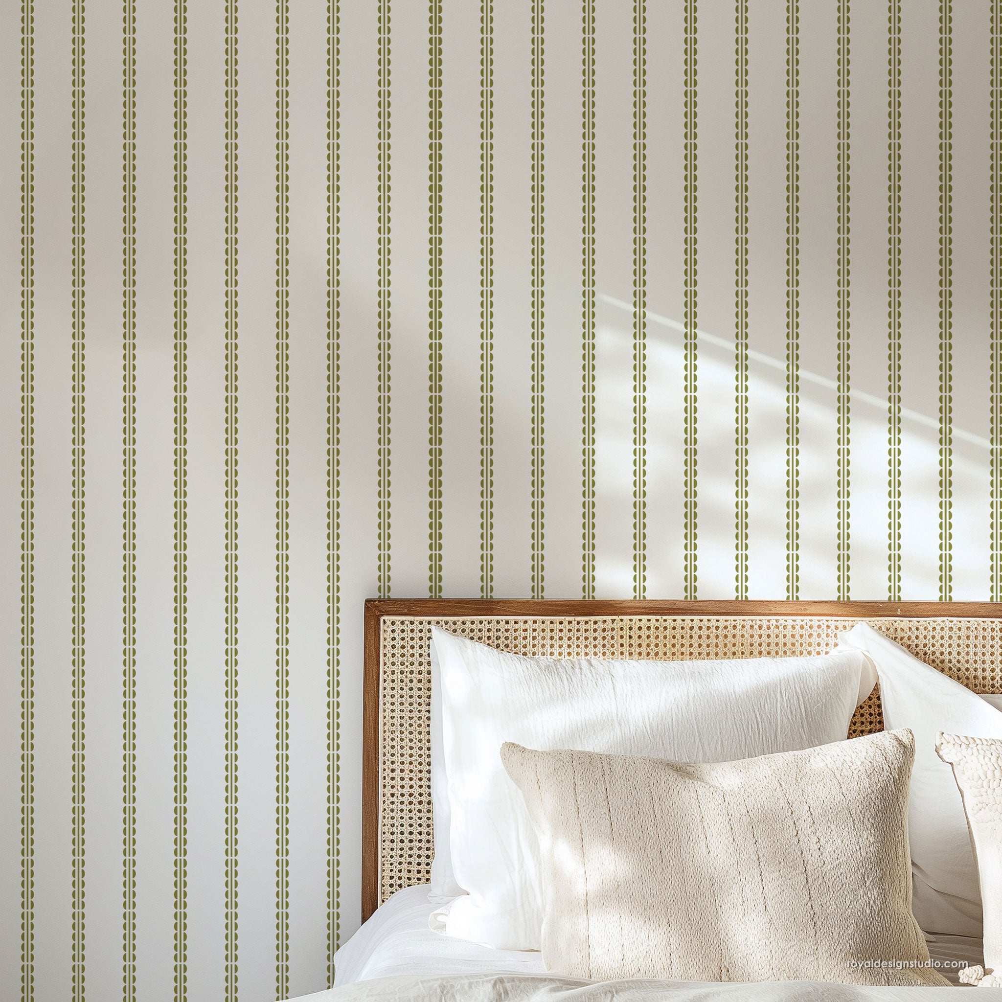 Vertical striped wall in cream and olive green shown in a styled bedroom setting above a bed with white linens and a woven wood headboard.