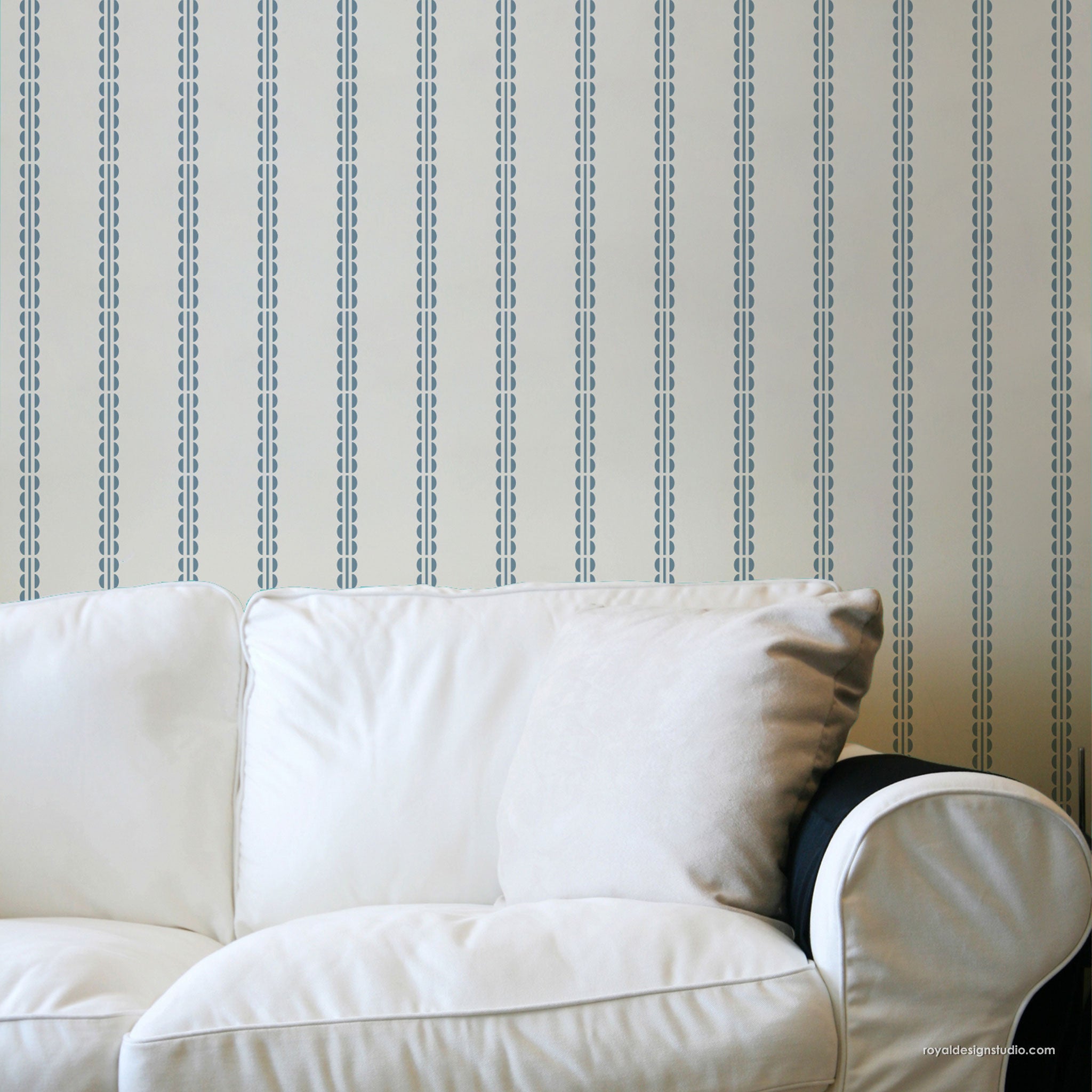 A close-up of a white upholstered sofa against a wall with repeating vertical blue dash patterns on a light beige background.