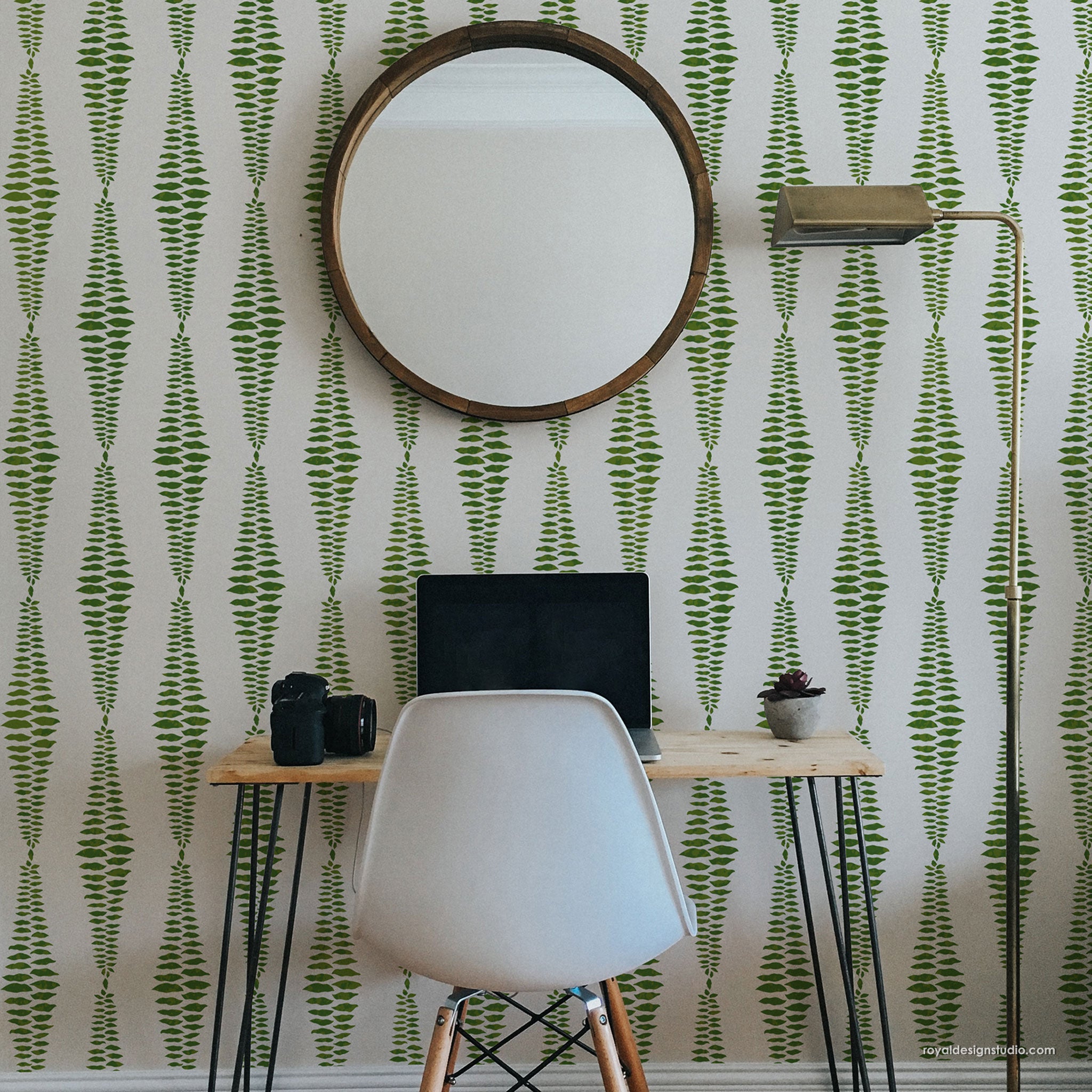 Room interior with a round mirror, desk, and chair against a green and white stenciled stripe wall.