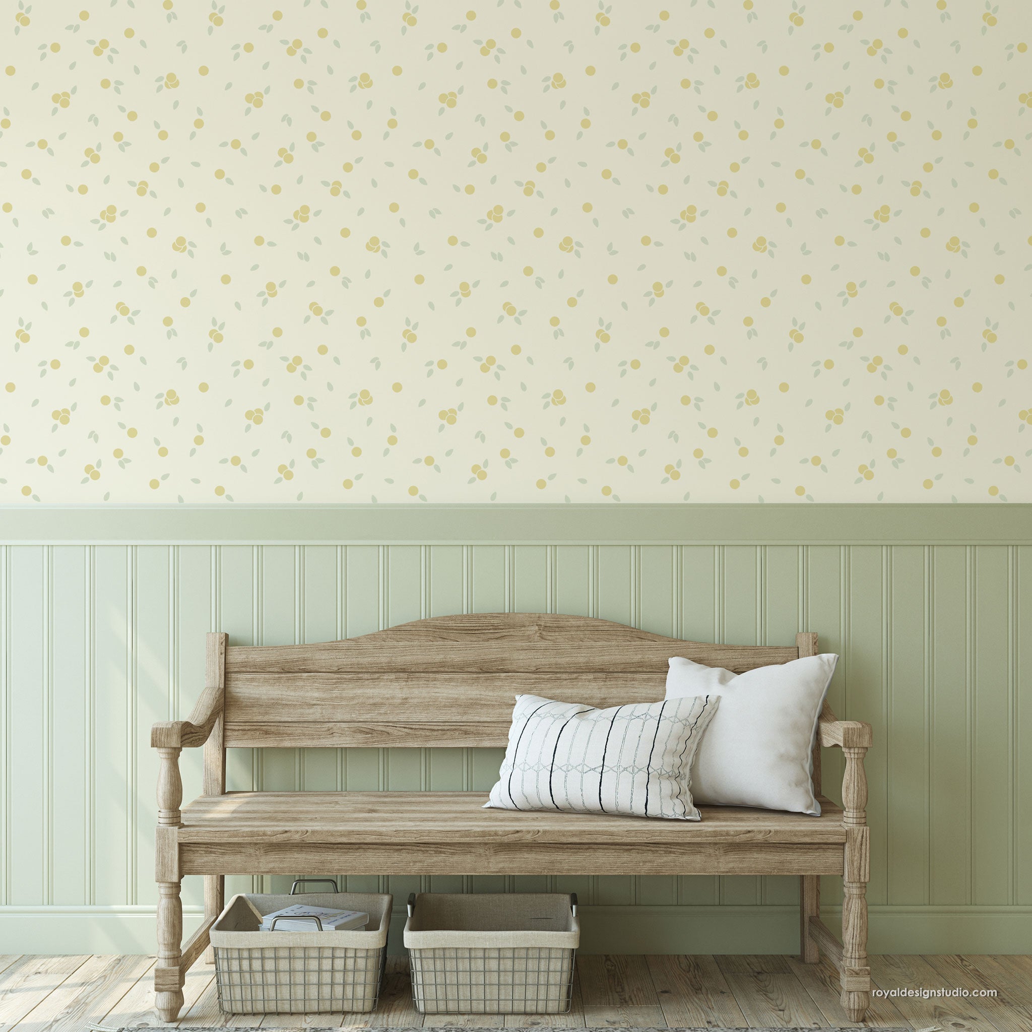 A styled interior scene showing a light wood bench against a wall with a pale yellow floral wall on the upper section and a sage green wainscoted lower section. Two white pillows rest on the bench, with two woven storage baskets underneath.