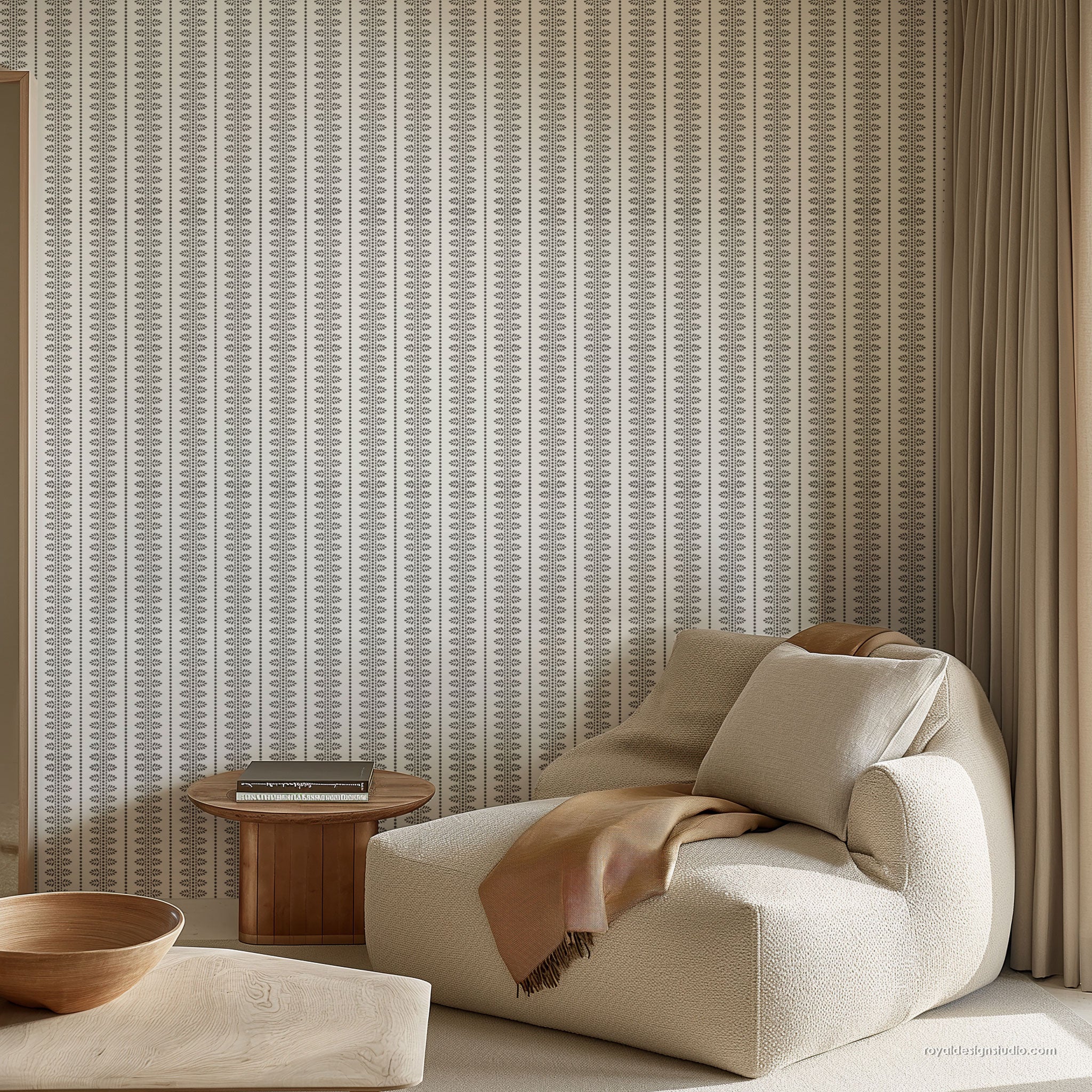 A styled interior corner featuring a cream bouclé lounge chair with a tan throw blanket, a small round wooden side table, and a wall covered in vertical striped wall with a subtle geometric pattern.