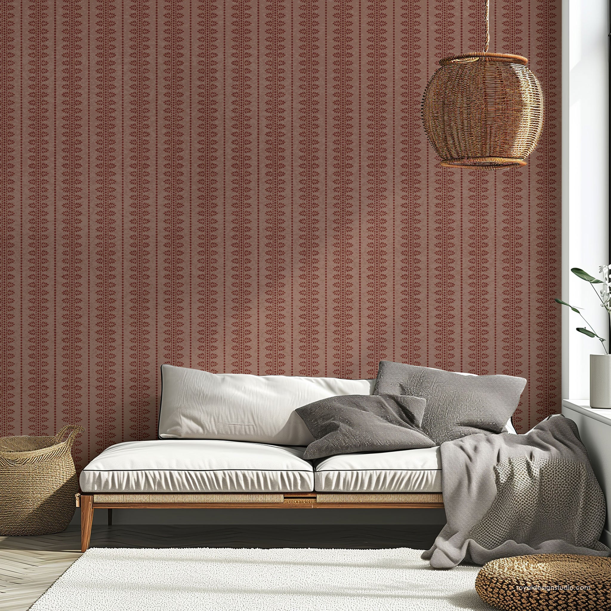 A styled interior scene showing a low wooden daybed with white cushions and gray pillows against a wall covered in vertically patterned rust-brown wall. A woven pendant light hangs above, with a white rug, basket, and plant visible in the room.