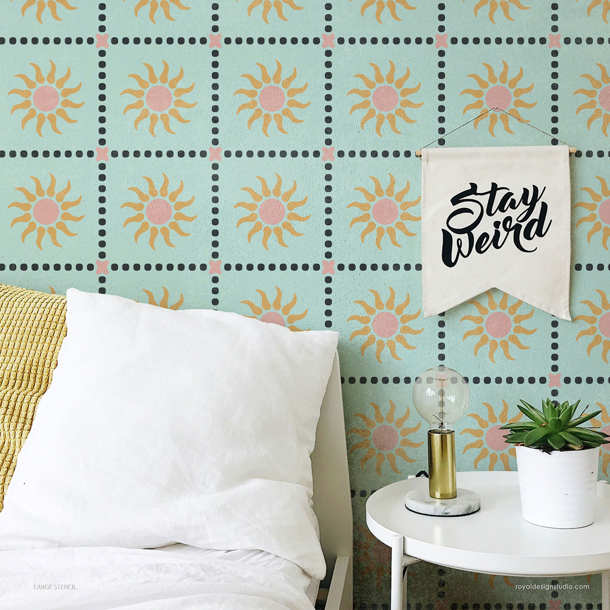 Room interior with sun-patterned wall stencil design, white pillow, and decorative lamp.