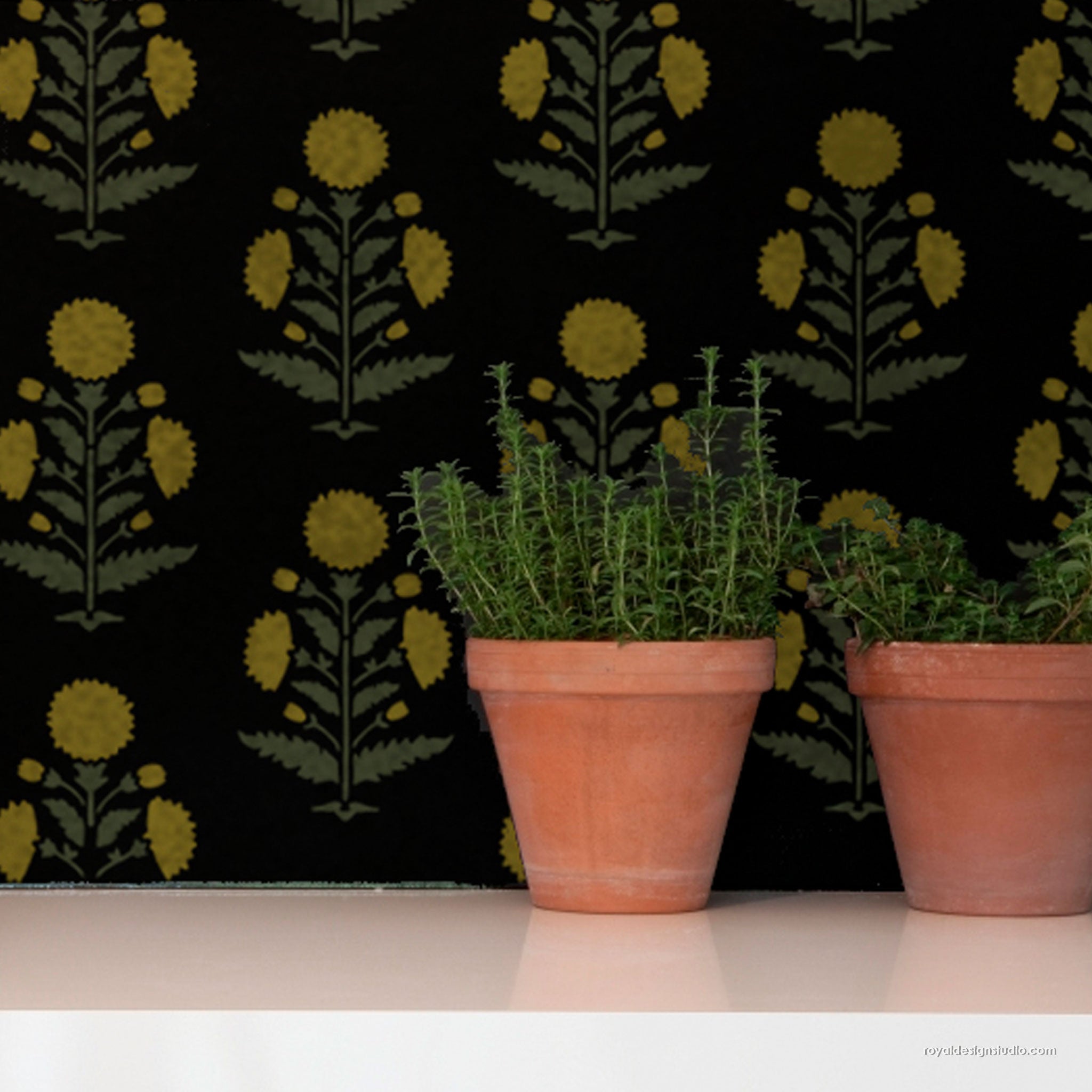 Black wallpaper with a repeating yellow and olive green floral pattern, styled with two terracotta pots containing green herbs on a white surface.