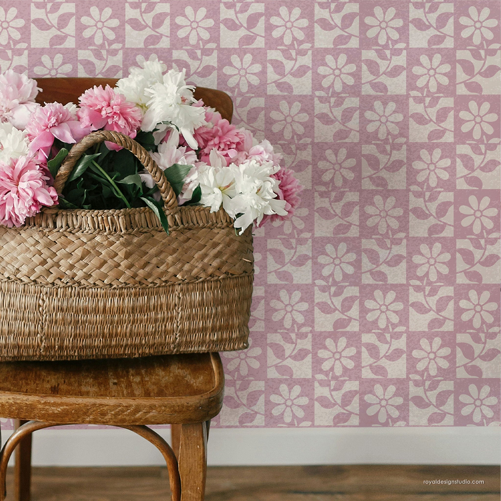 Wicker basket with flowers against a pink floral patterned wall.